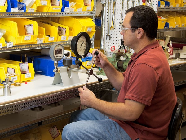 Calibration Technician Using a Pressure Comparator with a Reference Gauge