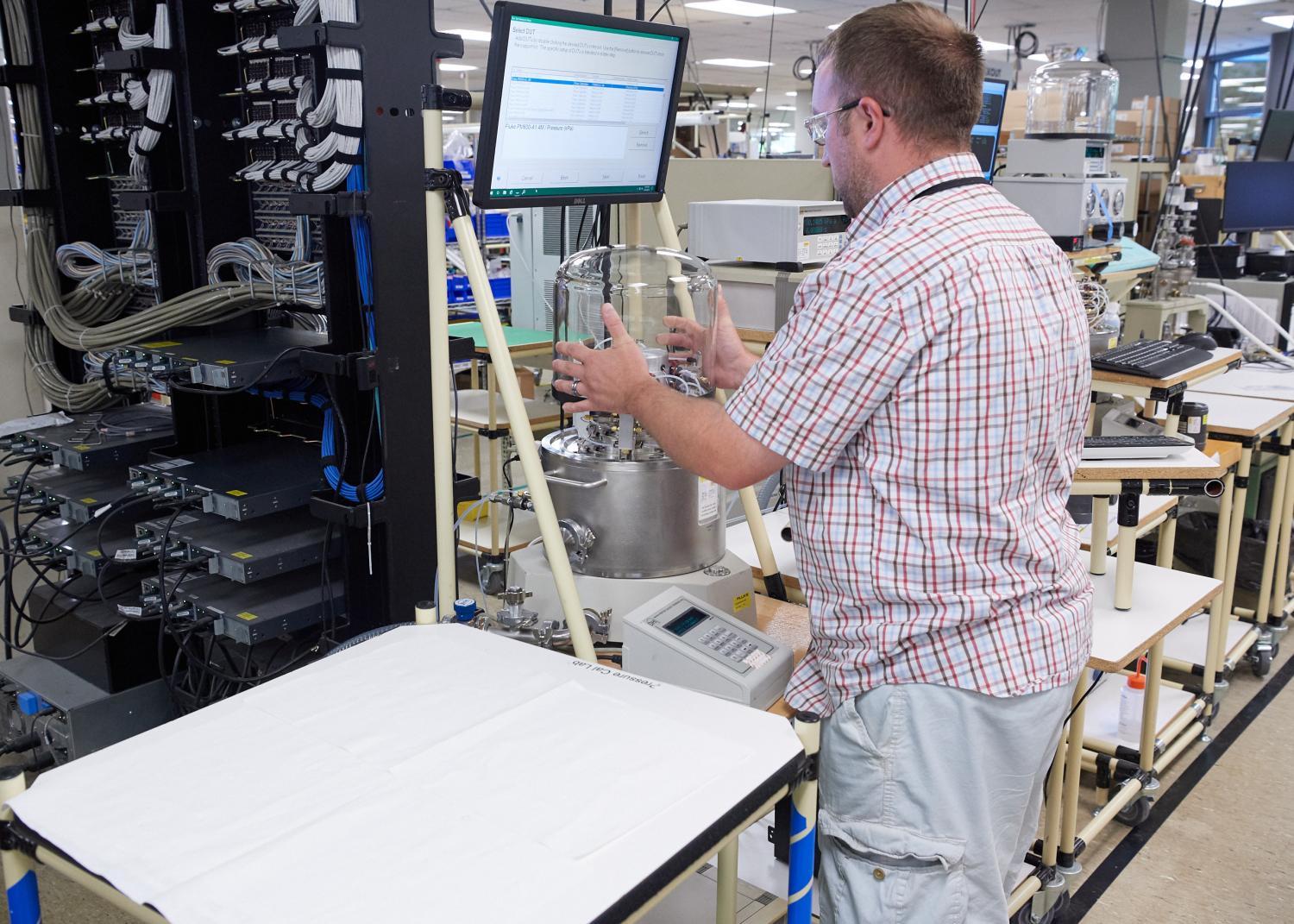 Maintenance professional in a lab configuring the Fluke 7610 piston gauge. 